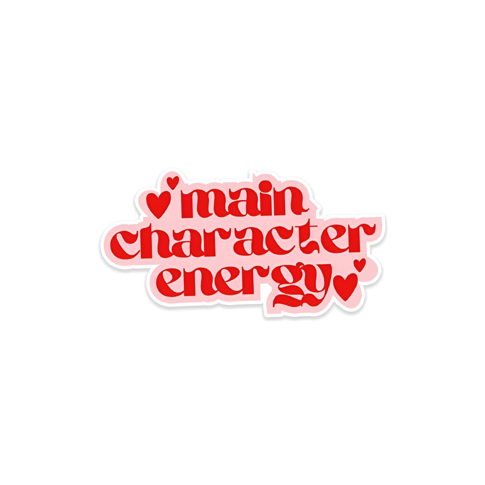 A rectangular sticker with a red background and a white horizontal stripe in the middle. In the center of the white stripe, black Devanagari text reads "घुमक्कड़" which translates to "Wanderer." The red background has faint travel-themed illustrations.