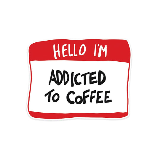 A rectangular sticker with a red background and a white horizontal stripe in the middle. In the center of the white stripe, black Devanagari text reads "घुमक्कड़" which translates to "Wanderer." The red background has faint travel-themed illustrations.