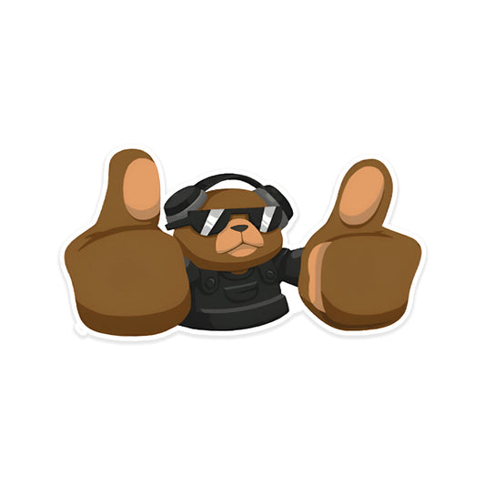 A rectangular sticker with a red background and a white horizontal stripe in the middle. In the center of the white stripe, black Devanagari text reads "घुमक्कड़" which translates to "Wanderer." The red background has faint travel-themed illustrations.