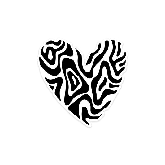 A rectangular sticker with a red background and a white horizontal stripe in the middle. In the center of the white stripe, black Devanagari text reads "घुमक्कड़" which translates to "Wanderer." The red background has faint travel-themed illustrations.