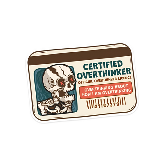 A rectangular sticker with a red background and a white horizontal stripe in the middle. In the center of the white stripe, black Devanagari text reads "घुमक्कड़" which translates to "Wanderer." The red background has faint travel-themed illustrations.